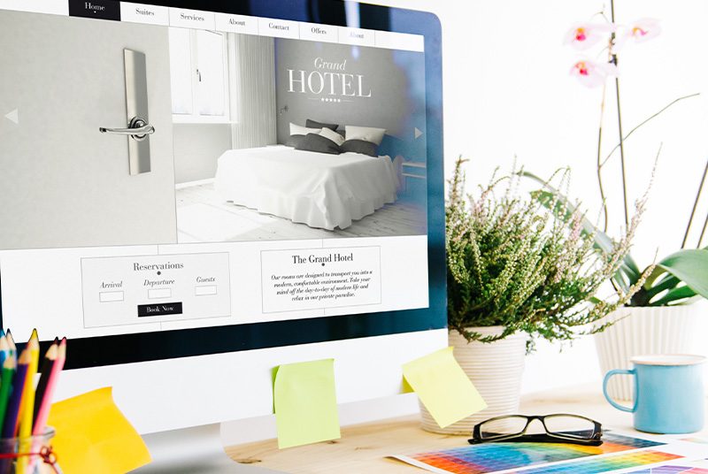 A hotel website being designed on a work computer screen|a written plan of a website with the hashtag #website