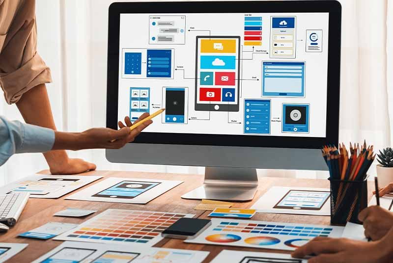 A team of designers look at a computer designing a website.